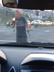 Street entertainers are common at stop lights. Here is one doing a routine with fire sticks throwing and twisting them. 